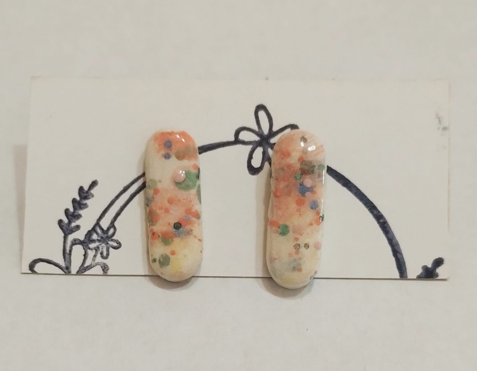 Un par de pendientes en una tarjeta con un diseño de flores.