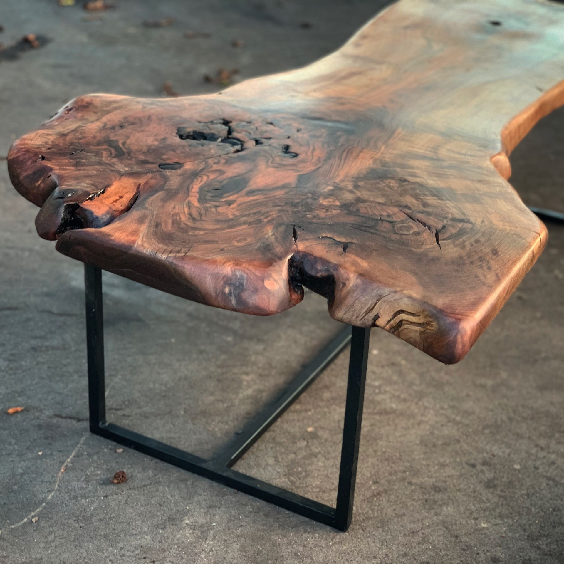 a walnut live edge table and coffee table with metal legs is sitting on the ground .