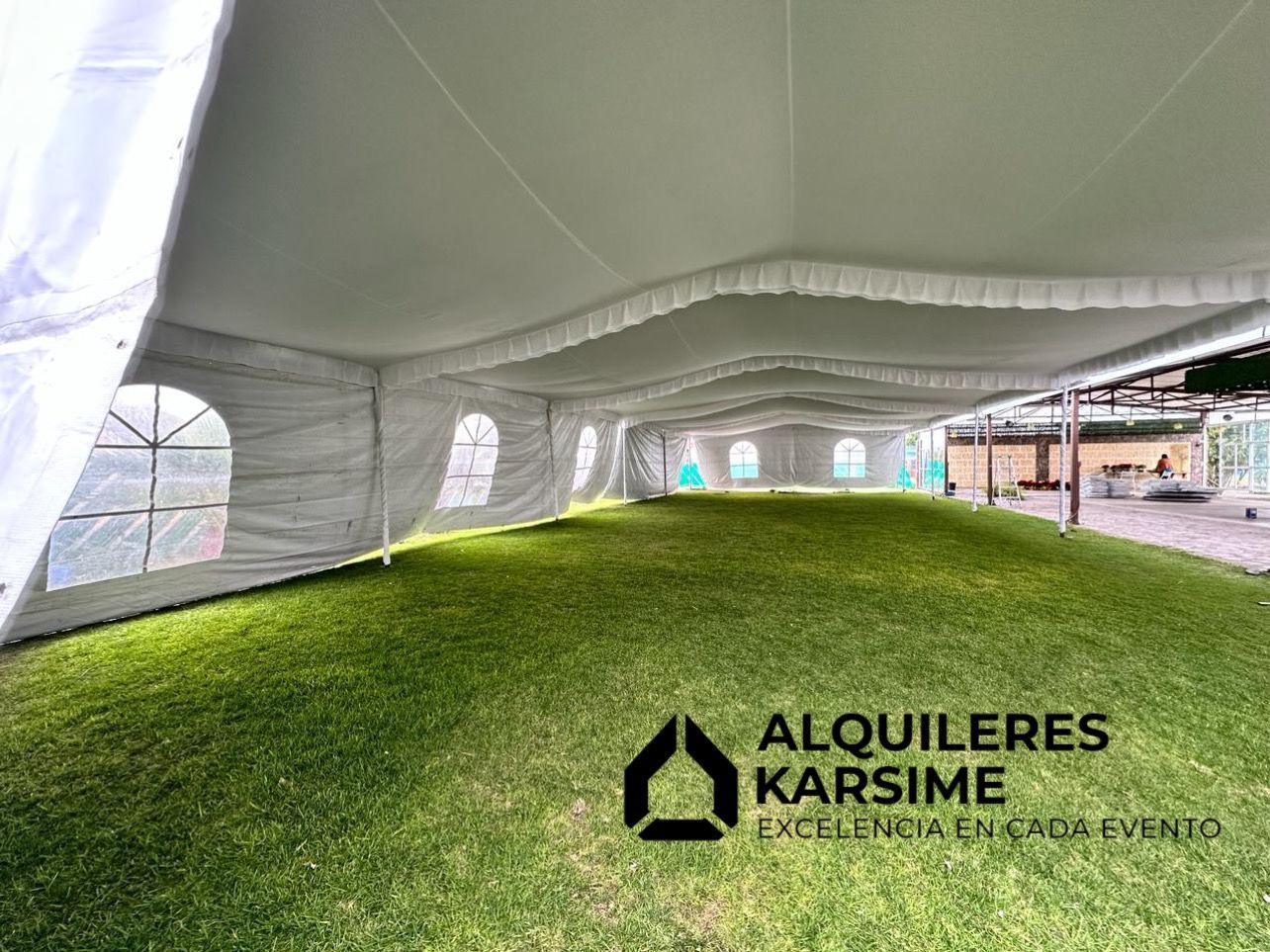 Una gran carpa blanca se encuentra sobre un exuberante campo verde.