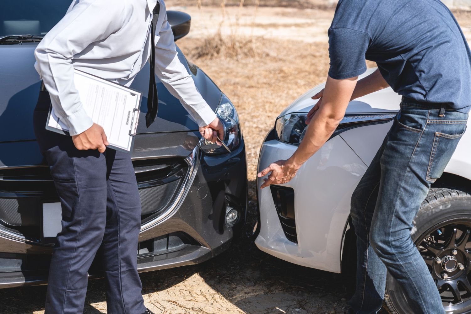 Two cars damaged in a collision; a man and woman stand nearby, looking concerned.