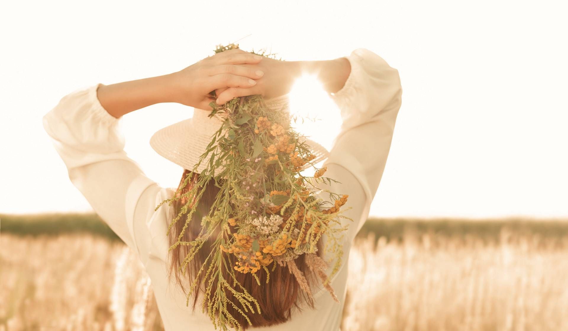 A woman is holding a bouquet of flowers in her hair in a field.