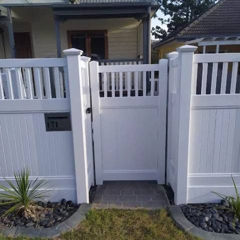 A white fence is surrounded by trees and grass