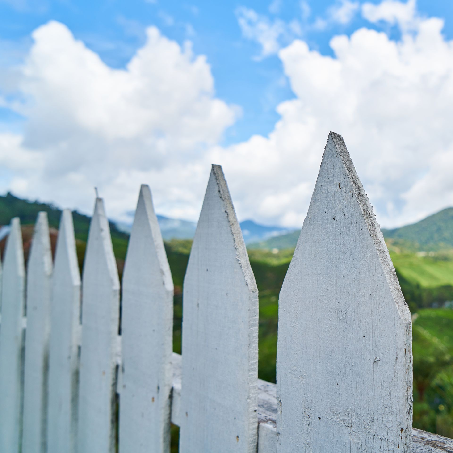 A white picket fence with mountains in the background
