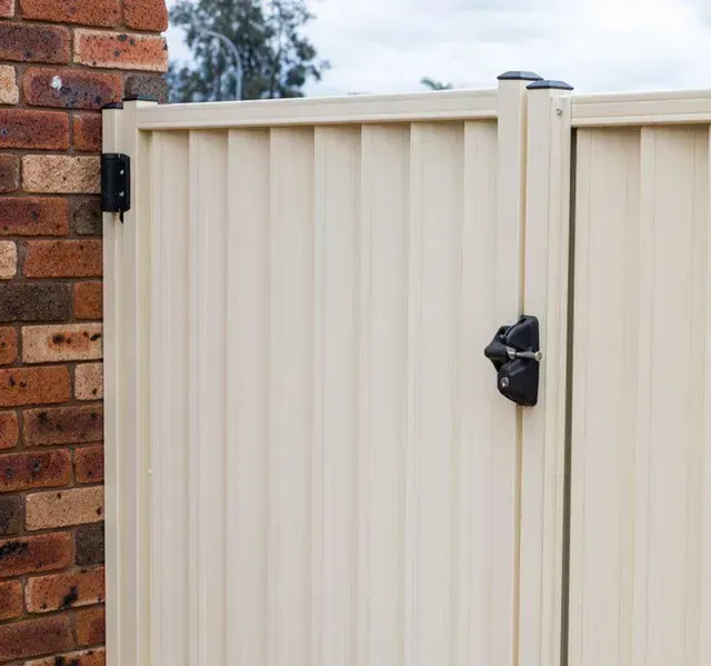 A white fence is sitting next to a brick wall.
