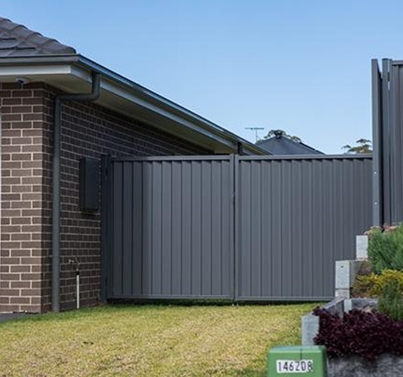 A brick house with a gray fence in front of it.