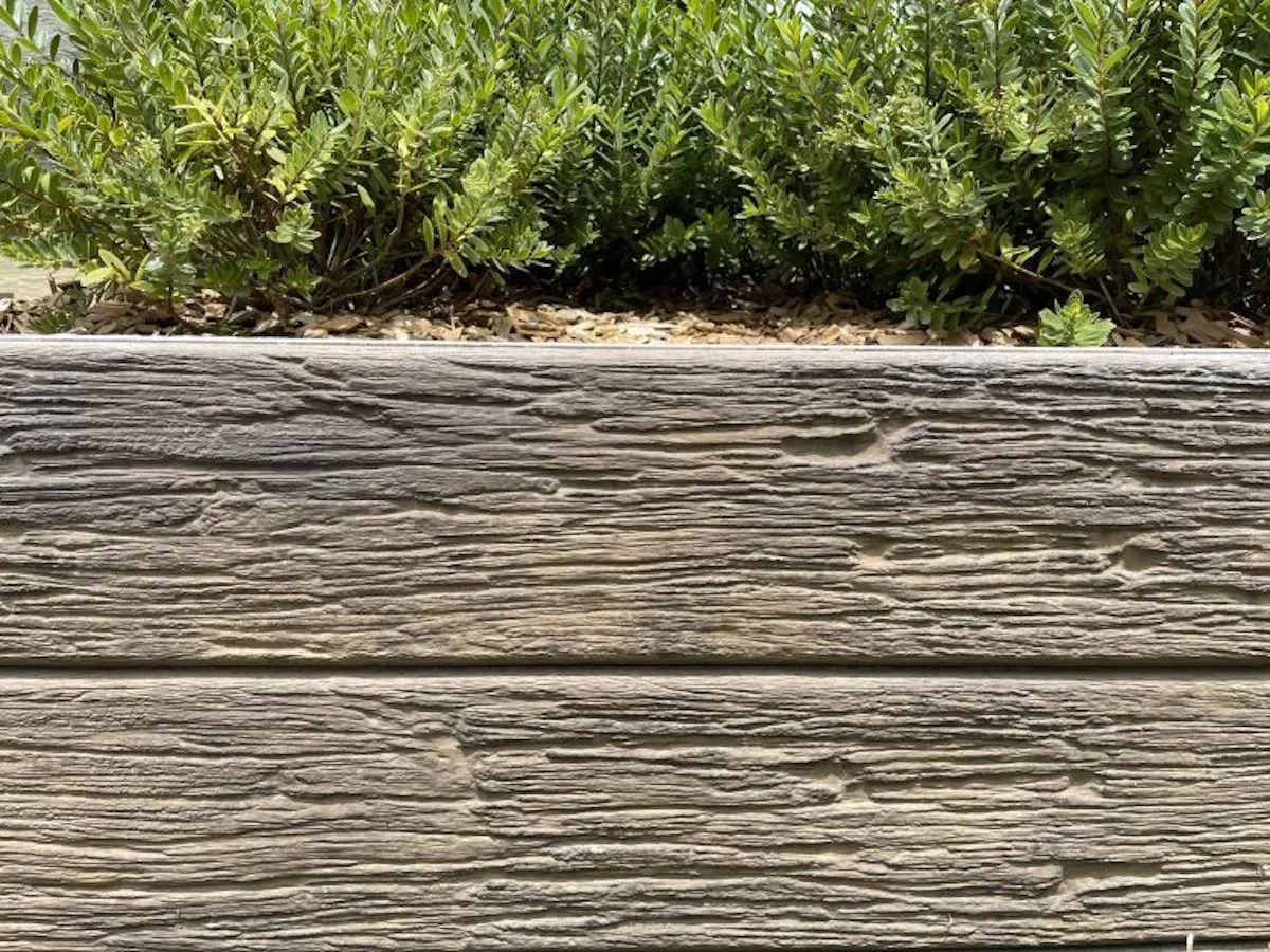 A close up of a wooden fence with a bush in the background.