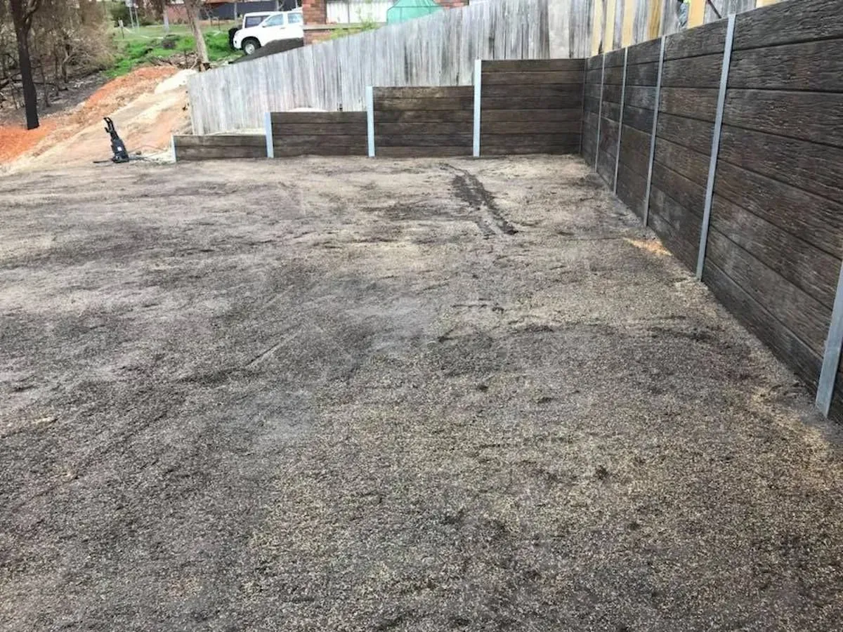 There is a fence in the background and a lot of dirt on the ground.