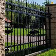 A black sliding gate is sitting in front of a stone wall.