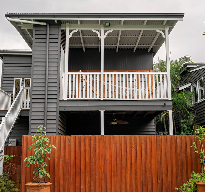 A house with a balcony and a wooden fence in front of it.