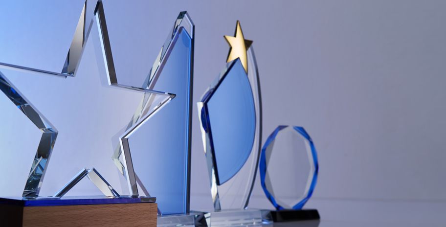 A man and woman pose in front of a conference backdrop. They are smiling and wearing name tags.