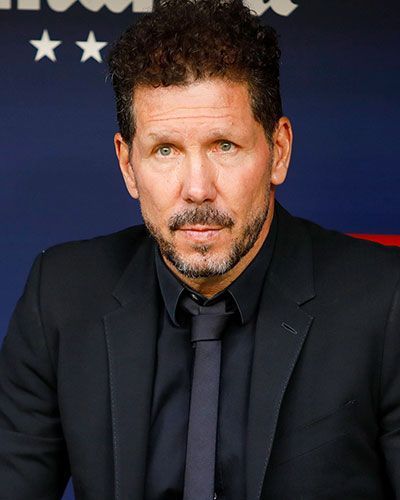 Diego Simeone con traje oscuro, mirando fijamente al espectador. Fondo rojo y azul.