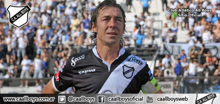 Jugador de fútbol con camiseta blanca y negra, de pie frente a una multitud.