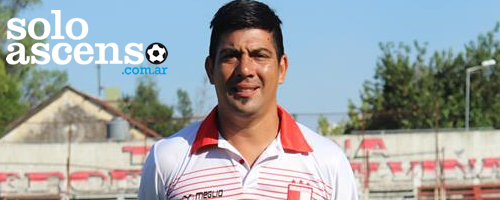 Hombre vestido con una camiseta de fútbol blanca y roja, de pie frente a un cielo azul y árboles.