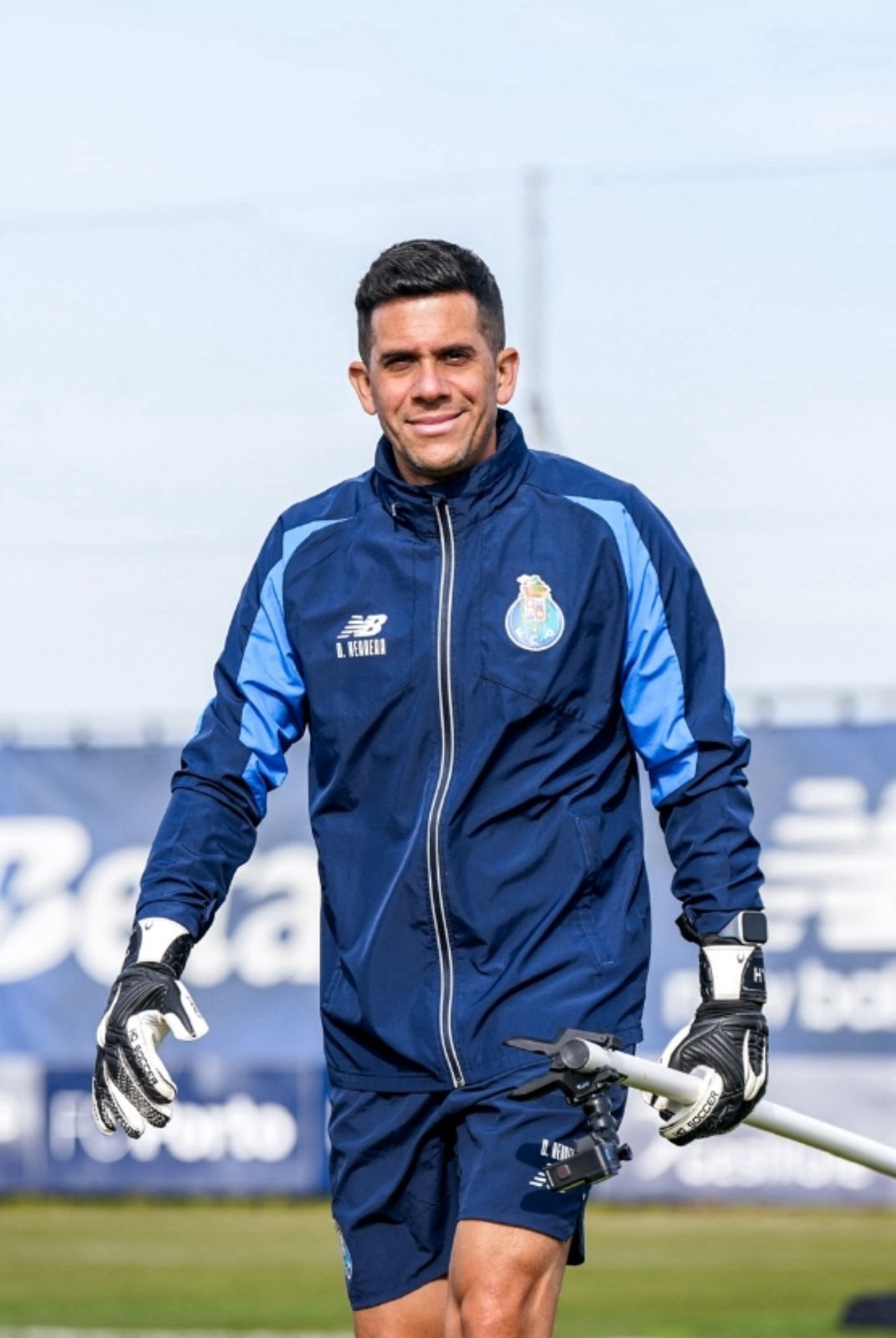 Portero de fútbol con ropa de entrenamiento azul, sonriendo al aire libre.