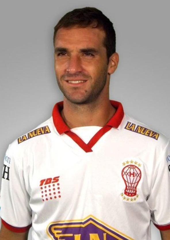 Hombre con una camiseta de fútbol blanca y roja, sonriendo.