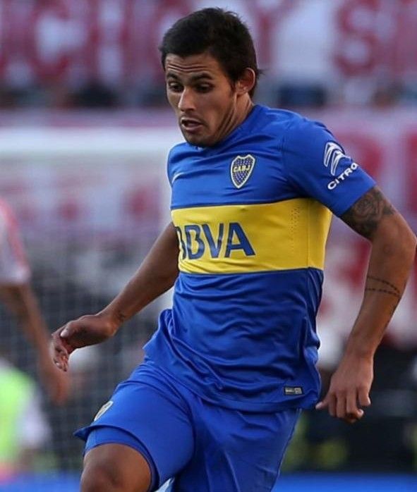 Jugador de fútbol con camiseta azul y amarilla, corriendo en el campo.