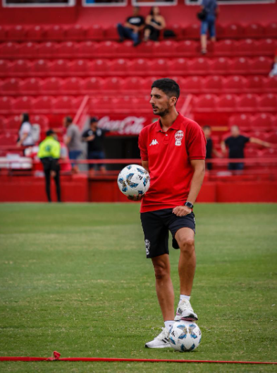 Jugador de fútbol calvo con una camiseta azul y negra y un parche de bandera italiana.