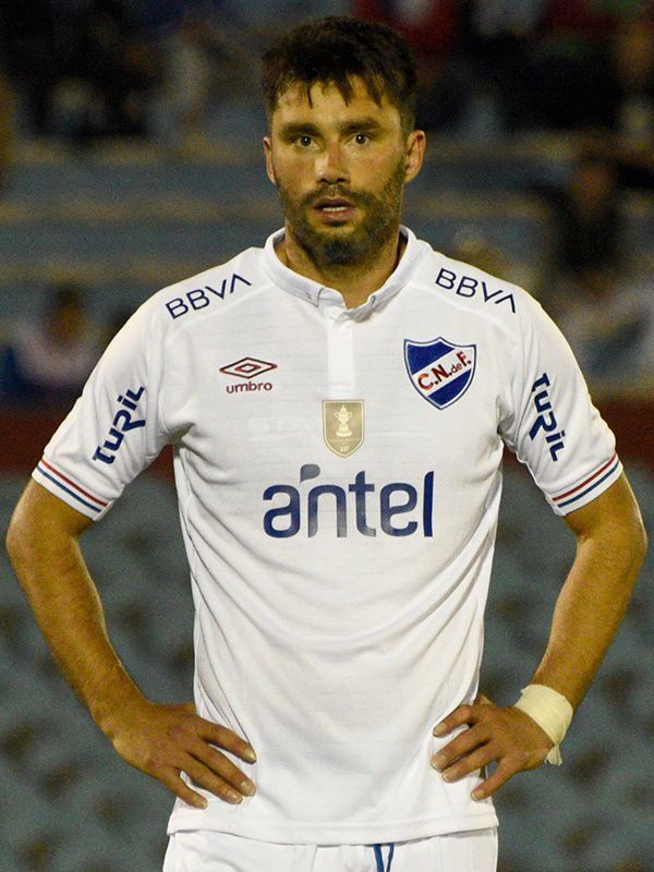 Hombre con una camiseta de fútbol blanca, con las manos en las caderas, de pie al aire libre.