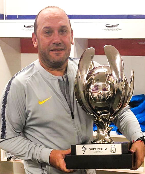 Un hombre sostiene un trofeo de plata en un vestuario.