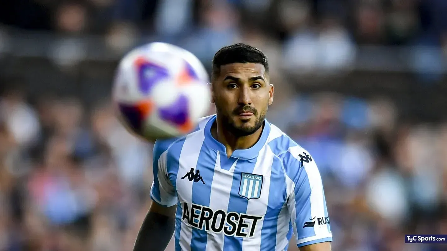 Jugador de fútbol con camiseta de rayas celeste y blanca, mirando fijamente el balón.