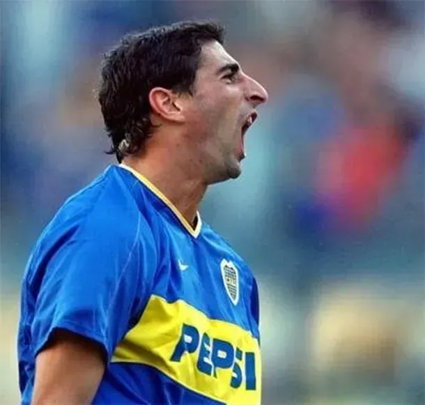 Jugador de fútbol con camiseta azul y amarilla gritando en un campo.