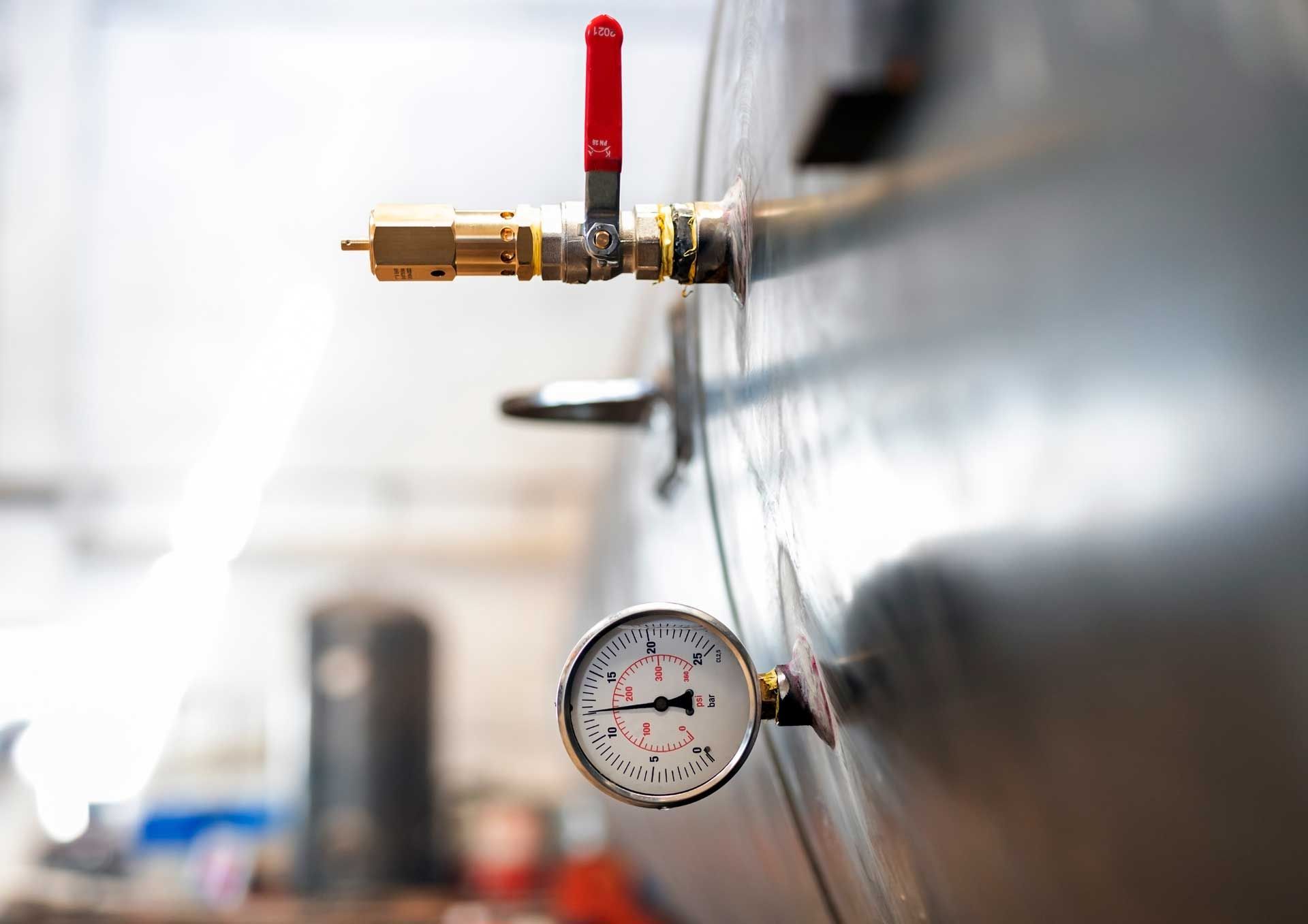 A close up of a pressure gauge attached to a pipe.