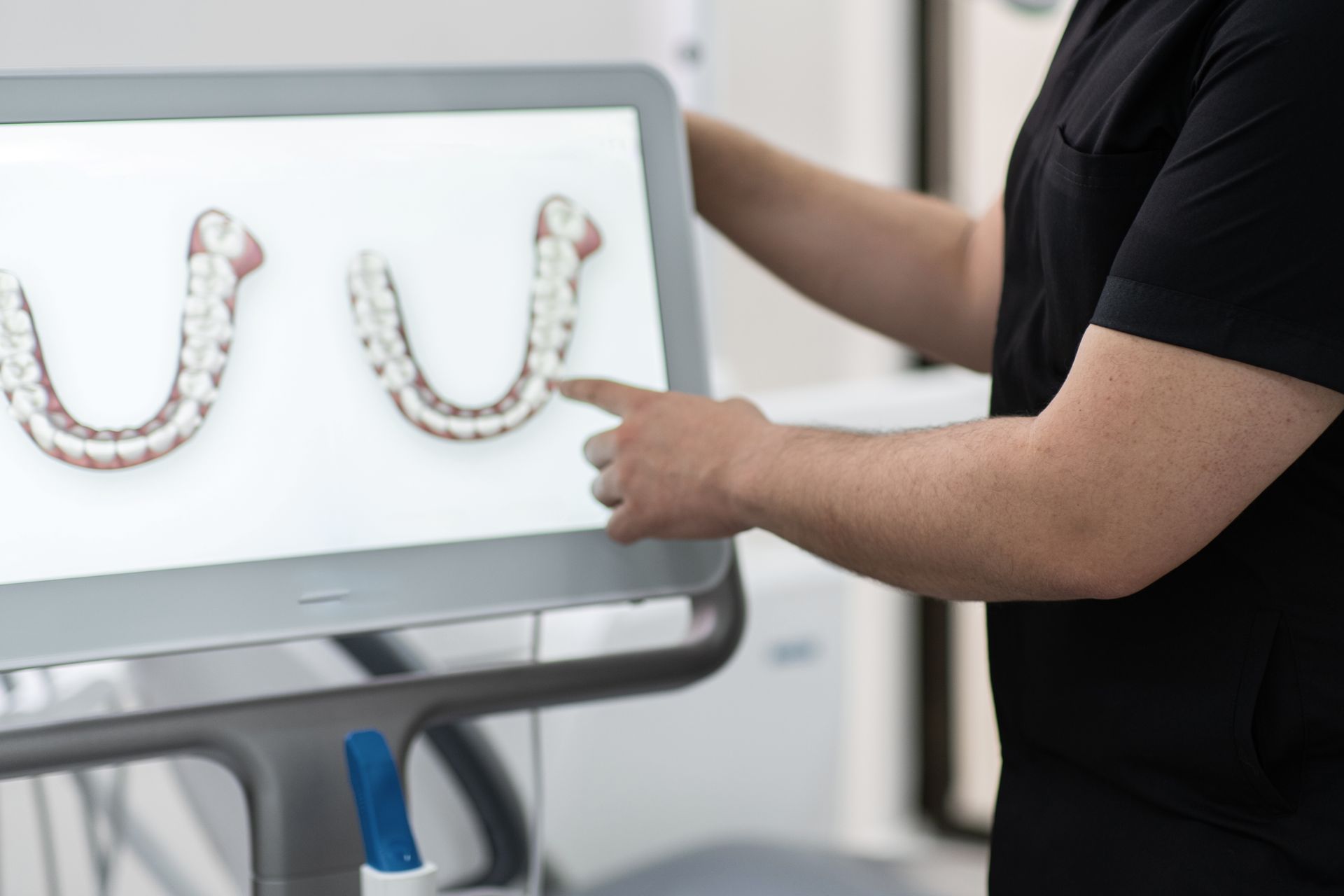 A man is pointing at a computer screen with a picture of teeth on it.