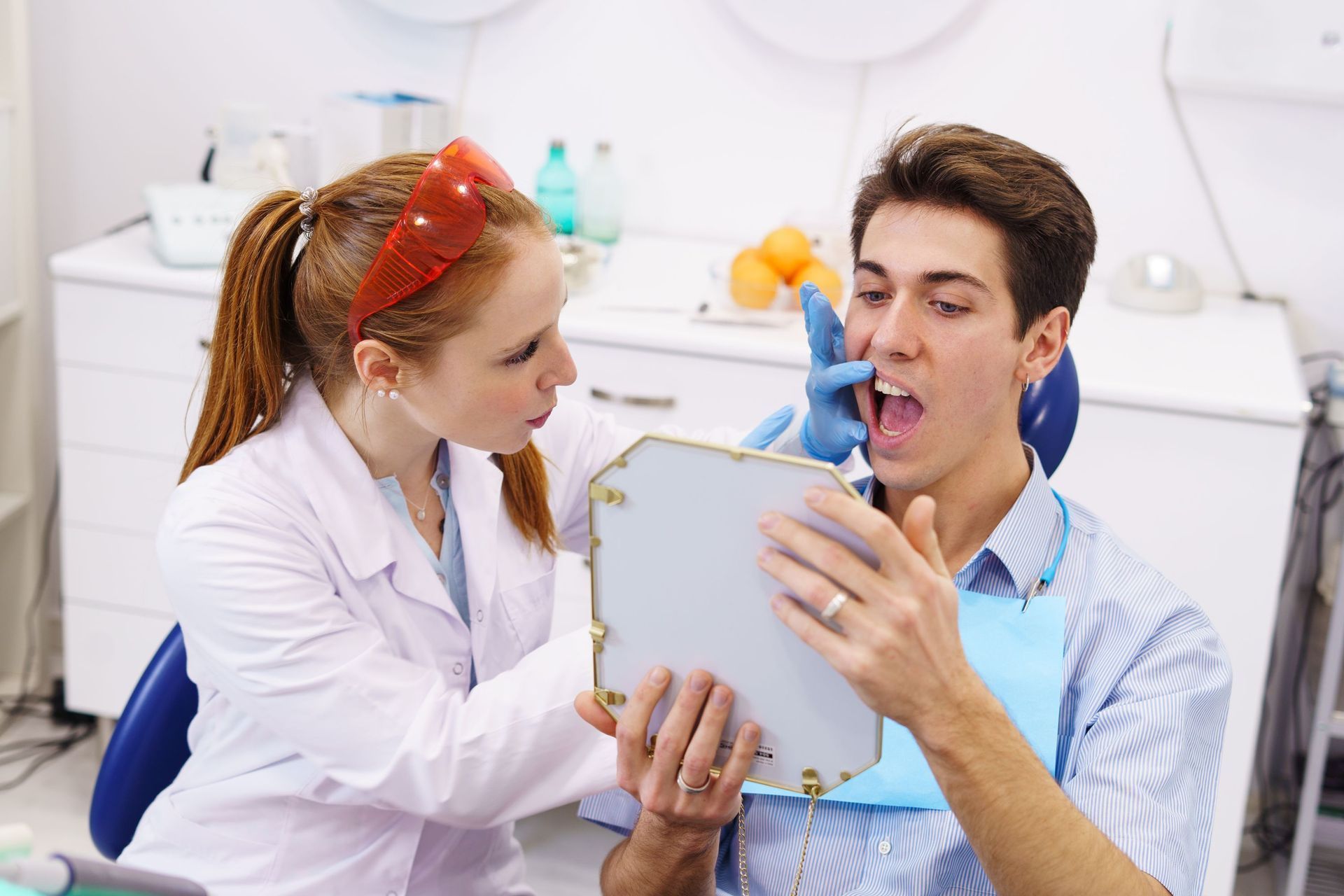 A dentist is examining a patient's teeth in a mirror.