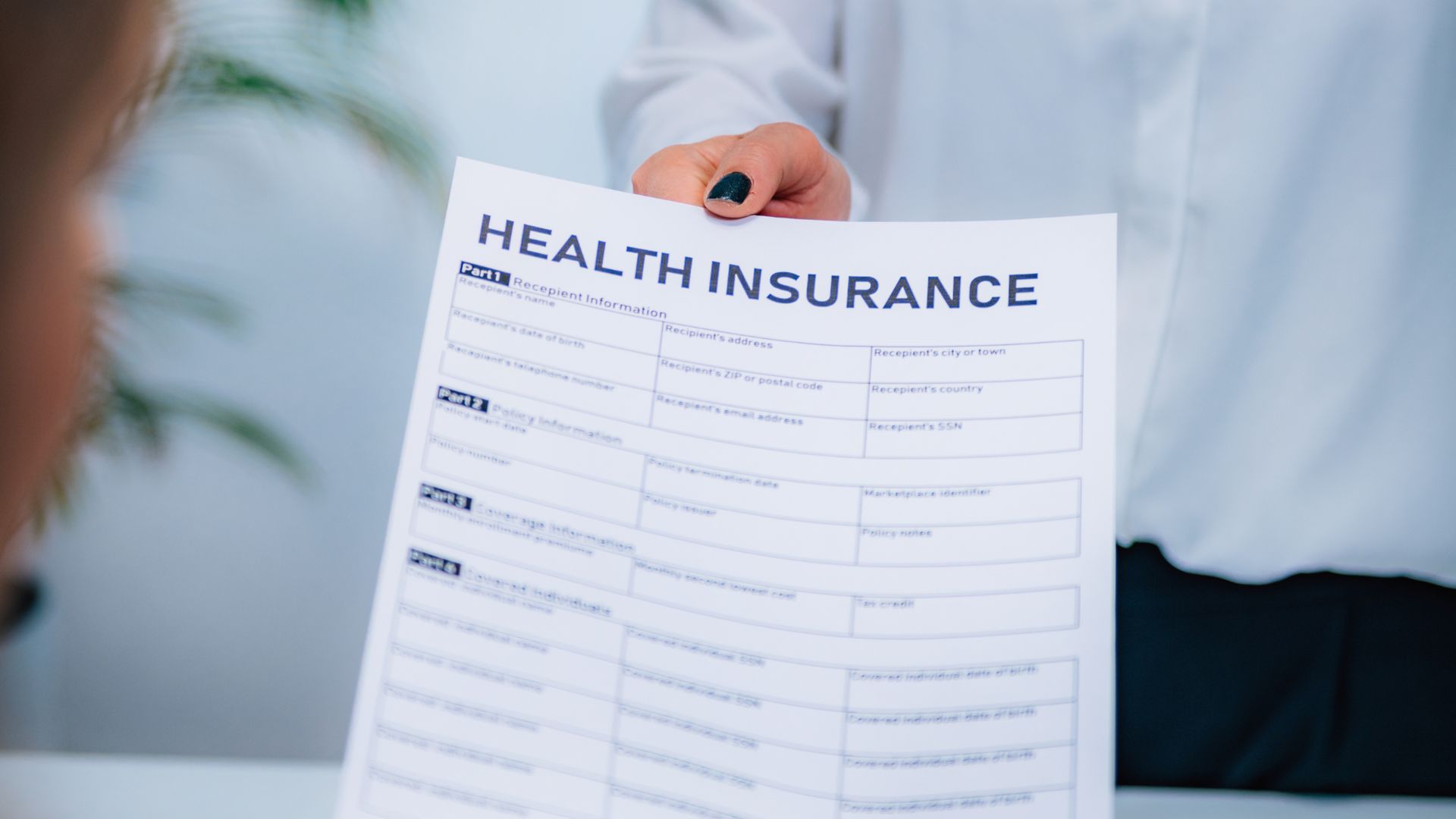 A woman is holding a health insurance form in her hand.