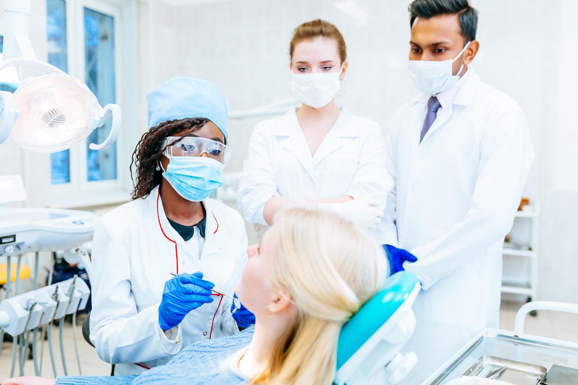 A group of dentists are examining a patient 's teeth in a dental office.