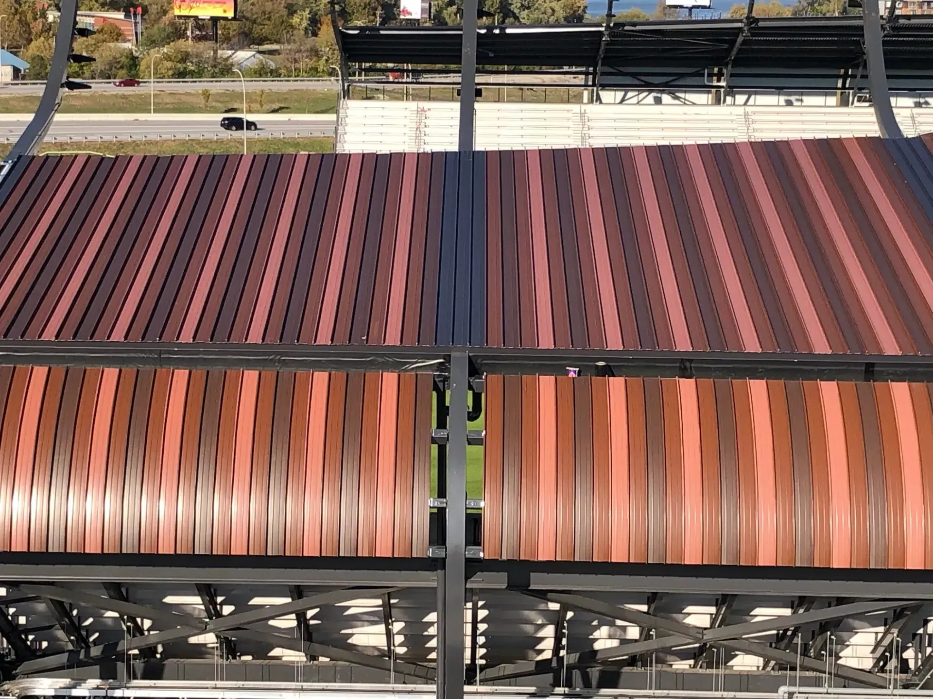 Overhead view of a stadium roof with brown, wavy and straight metal slats.