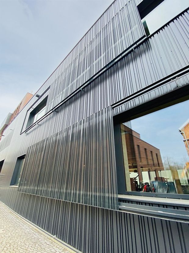 Modern building exterior with patterned metal panels and window reflections.