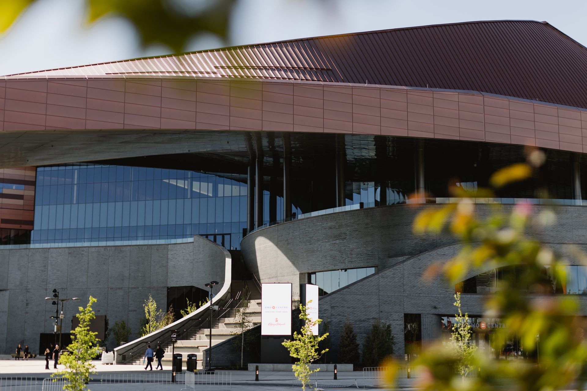 Modern building with copper roof and concrete facade, glass windows, and steps leading to the entrance.