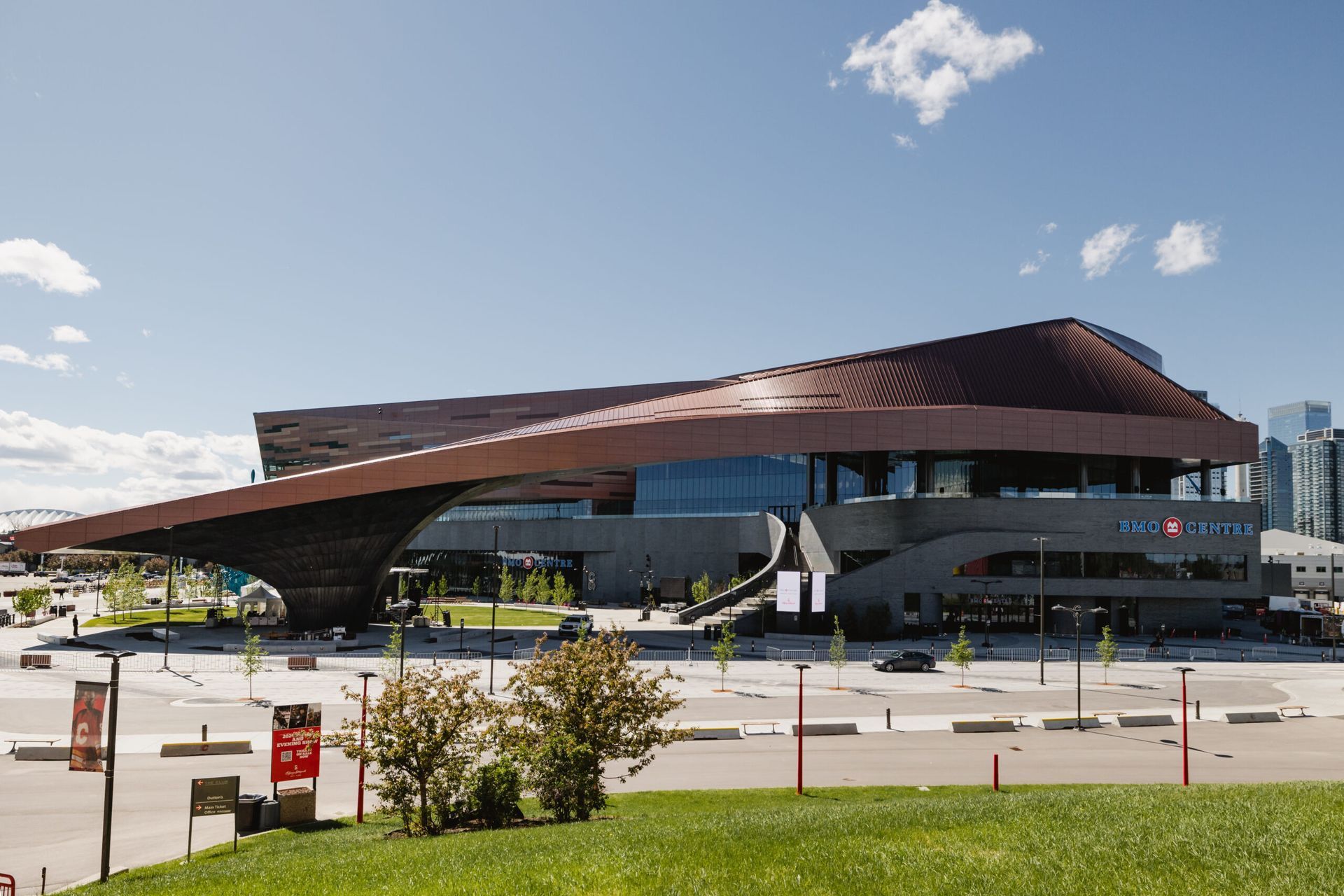 Modern, copper-colored building with large overhang; blue sky.