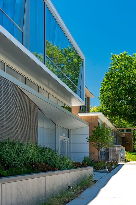 Modern building exterior with glass windows, brick, and concrete under a bright blue sky.
