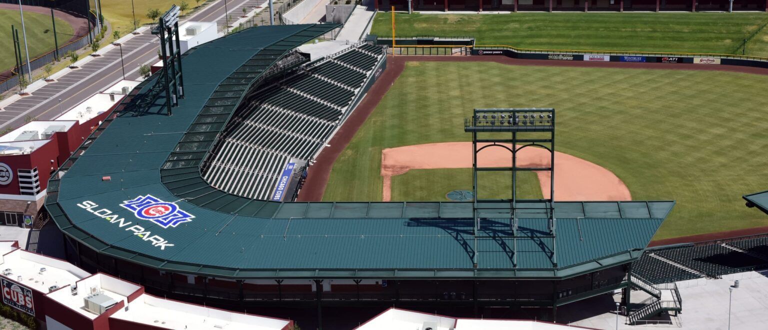 Aerial view of a baseball stadium with a green roof, field, and seating.