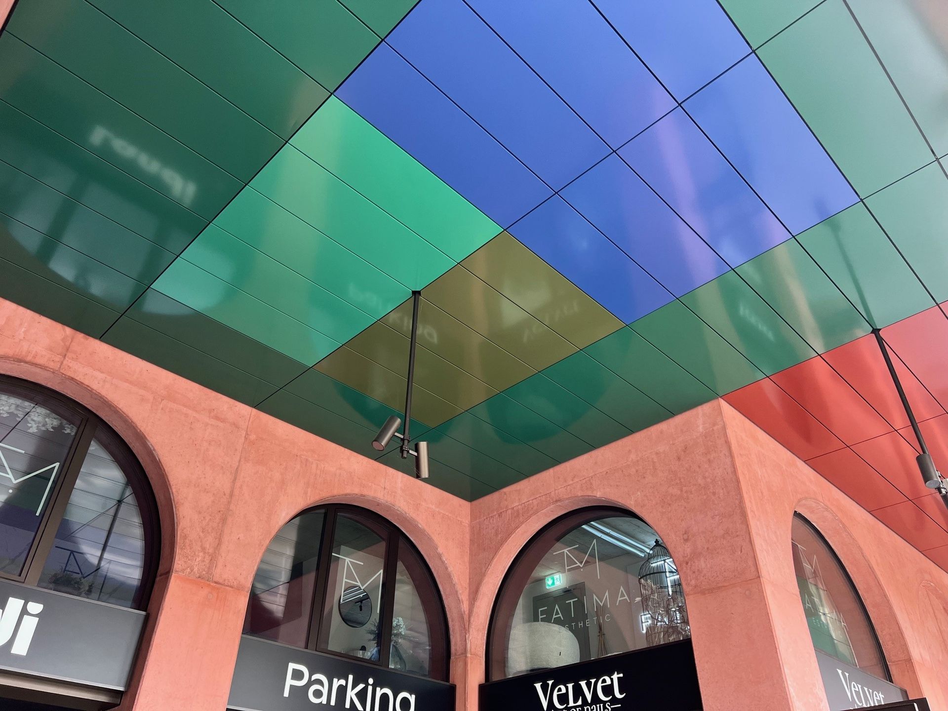 Colorful tiled ceiling above a red-toned building with arched entryways; 