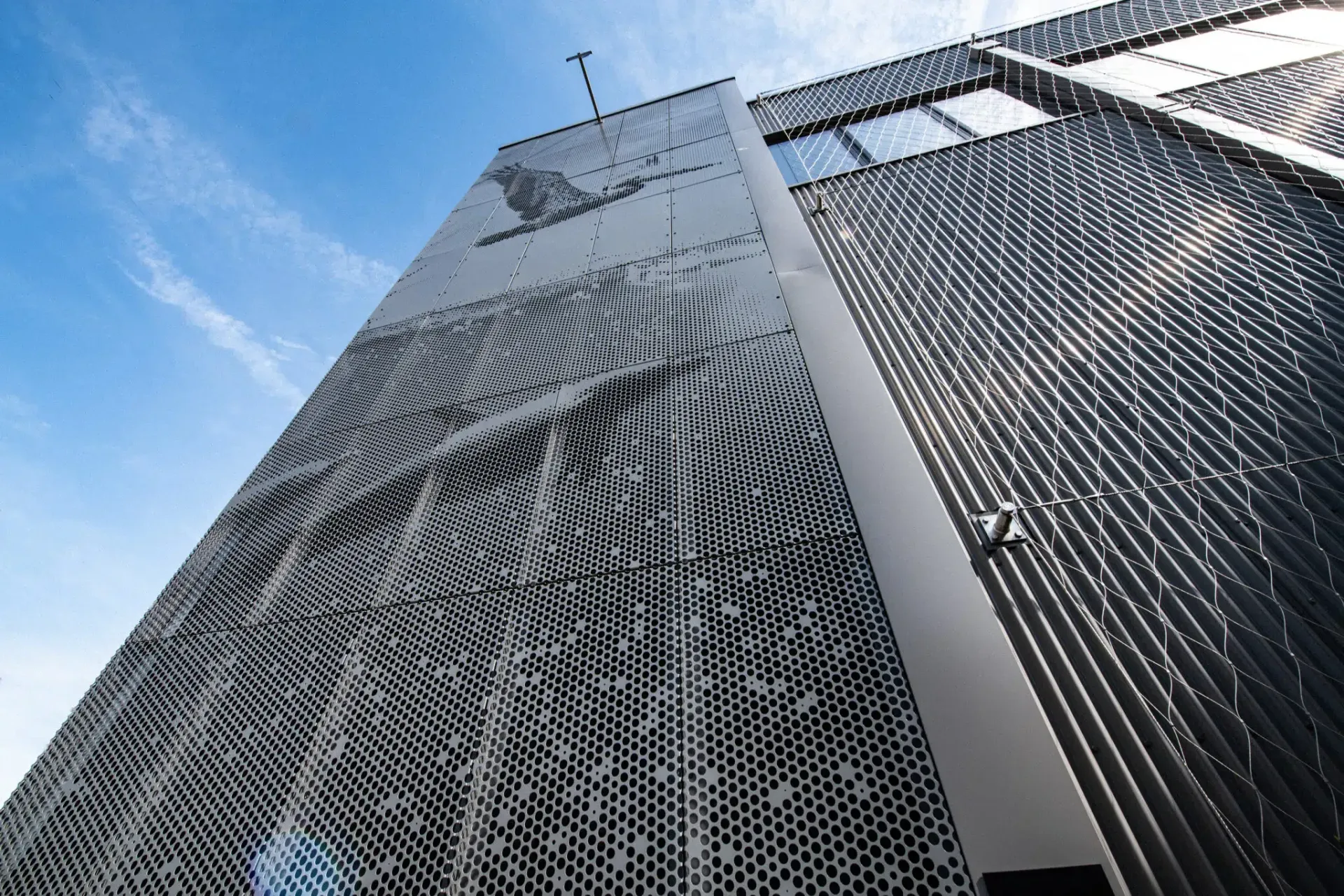 Modern building exterior with patterned metal facade against a blue sky.