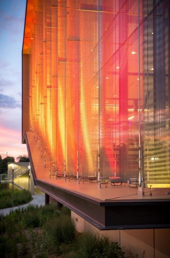 Modern building facade with illuminated orange and red panels against a twilight sky.