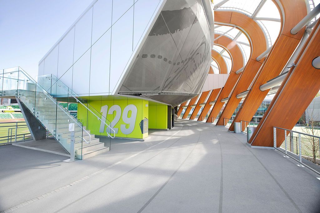 Modern building with glass, metal, and wooden archway, featuring a green wall with large white numbers.