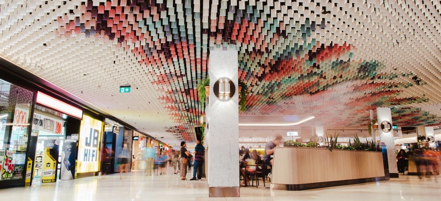 Interior of a shopping mall with colorful ceiling art and people walking.
