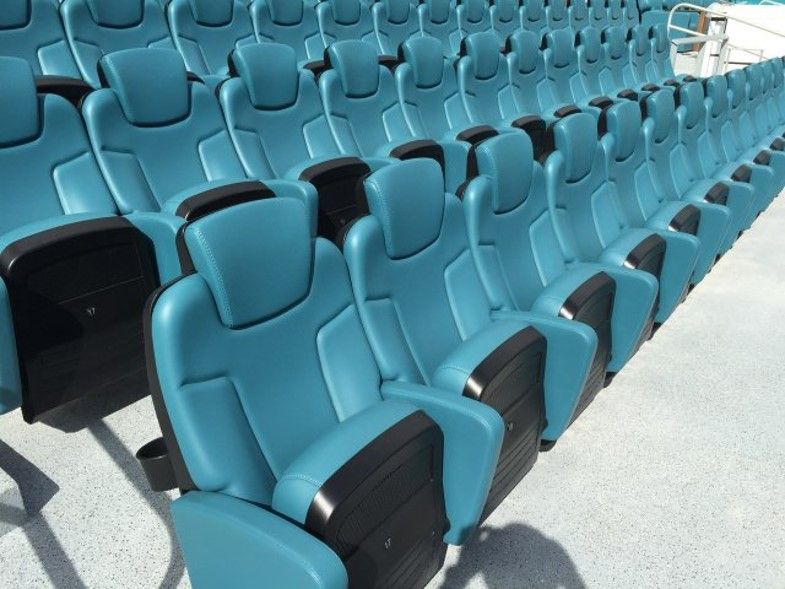 Empty teal stadium seats with black armrests and headrests.