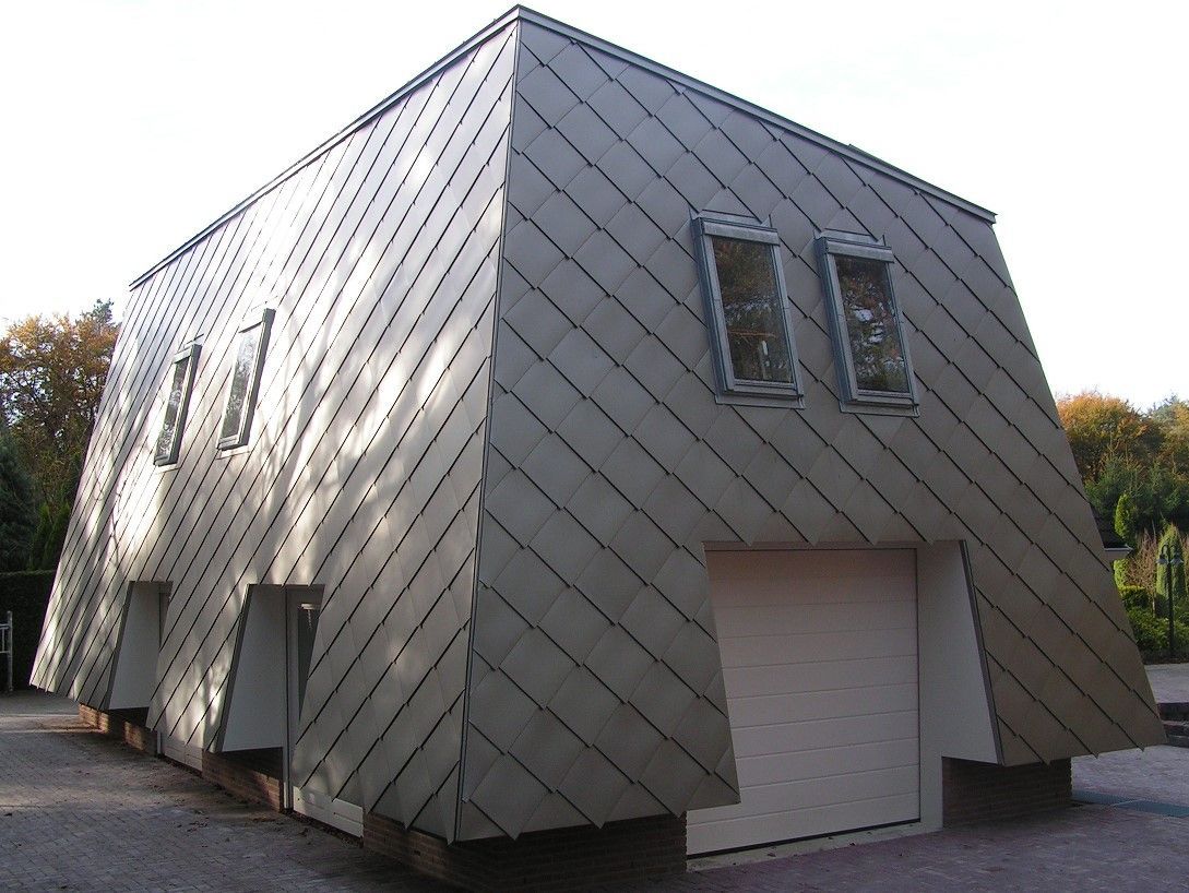 Angular silver building with tilted roof and small windows, white door.