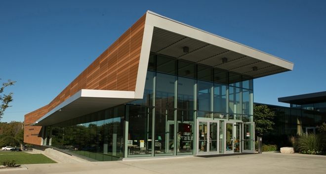 Modern building with glass walls and angled roof under blue sky.