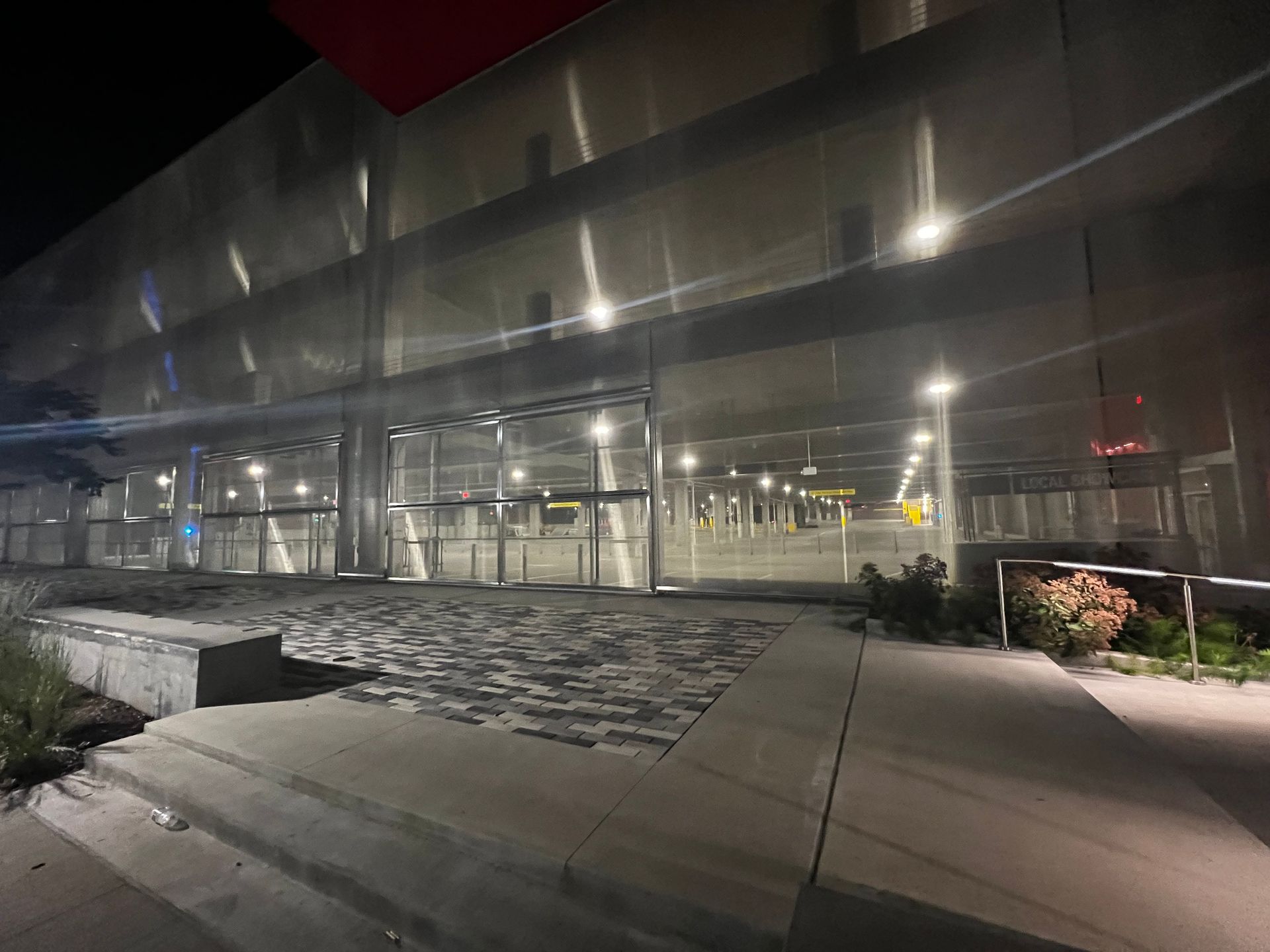 Exterior view of a modern building at night. Glass doors open to a brightly lit interior.