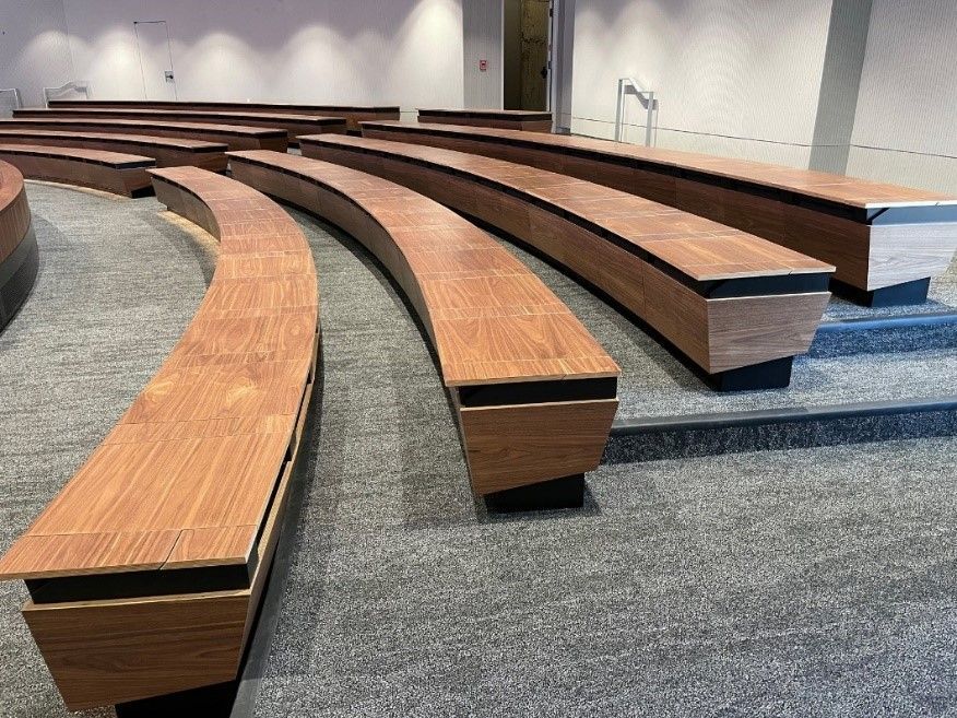 Curved wooden benches on steps in a modern auditorium, possibly for seating.