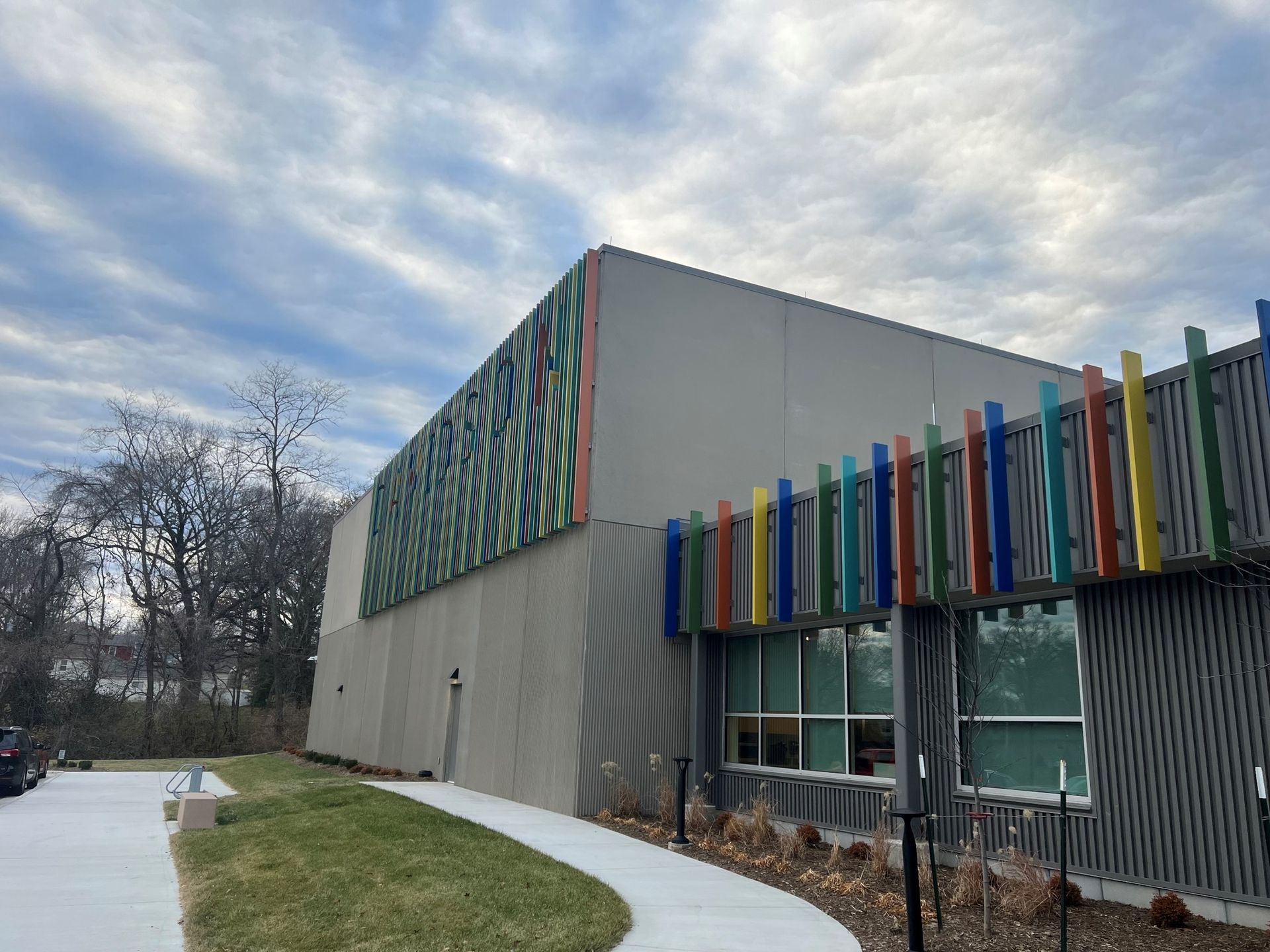 Modern building with colorful accents, cloudy sky.