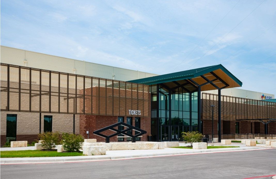 Exterior of modern brick building with glass entrance, beneath a green canopy.