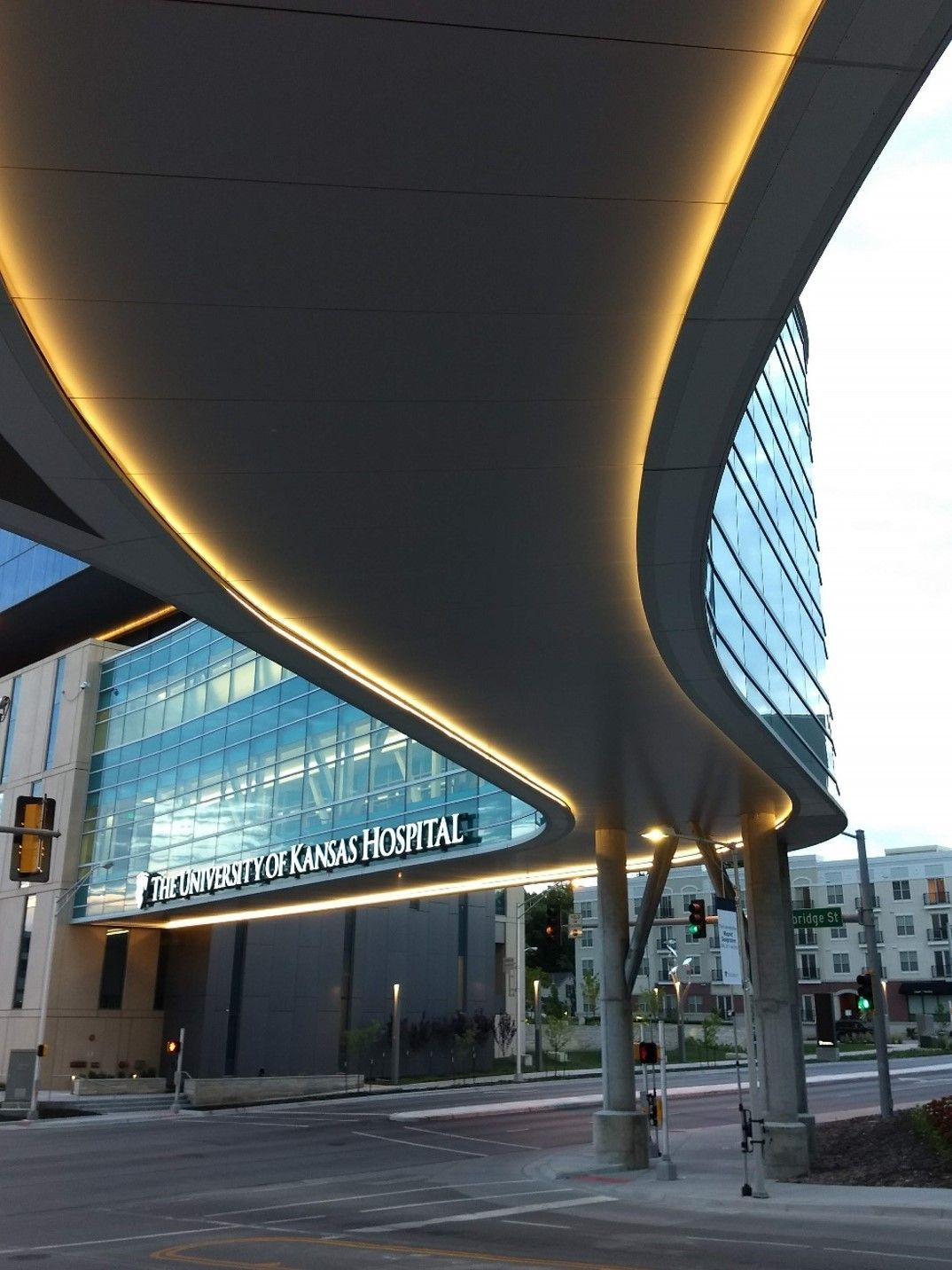 Curving canopy over The University of Kansas Hospital entrance with lit trim and glass facade.