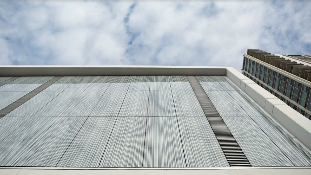 Modern building exterior with reflective glass facade against a cloudy sky.